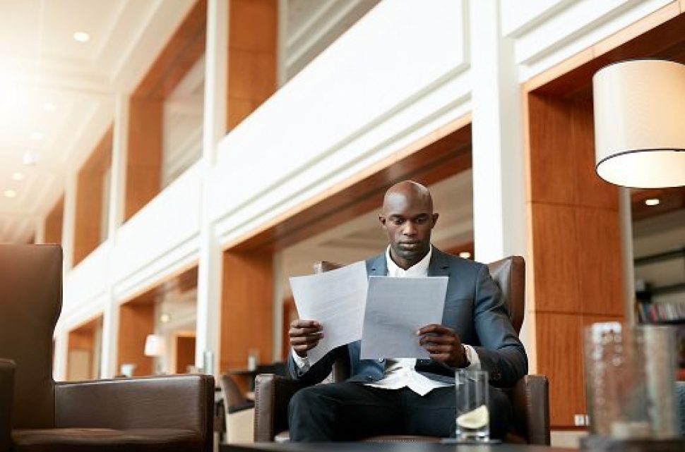 business-executive-at-lobby-reading-documents-P3JLXKP